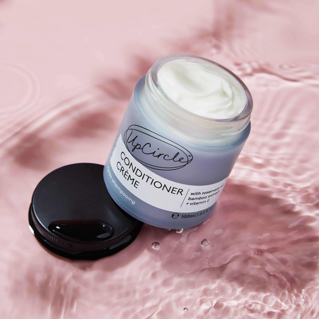 Jar of UpCircle Conditioner Crème on a pink textured background