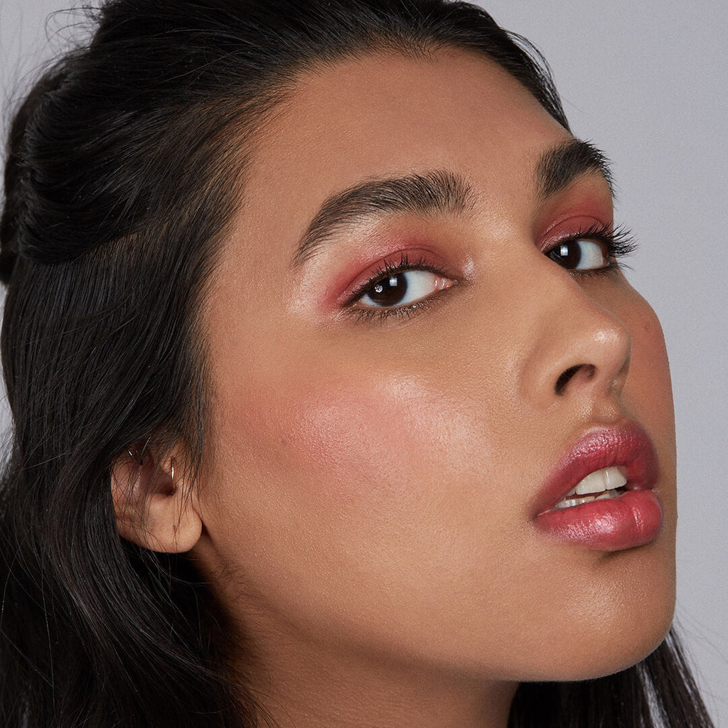 Close-up of a woman with makeup on a plain background