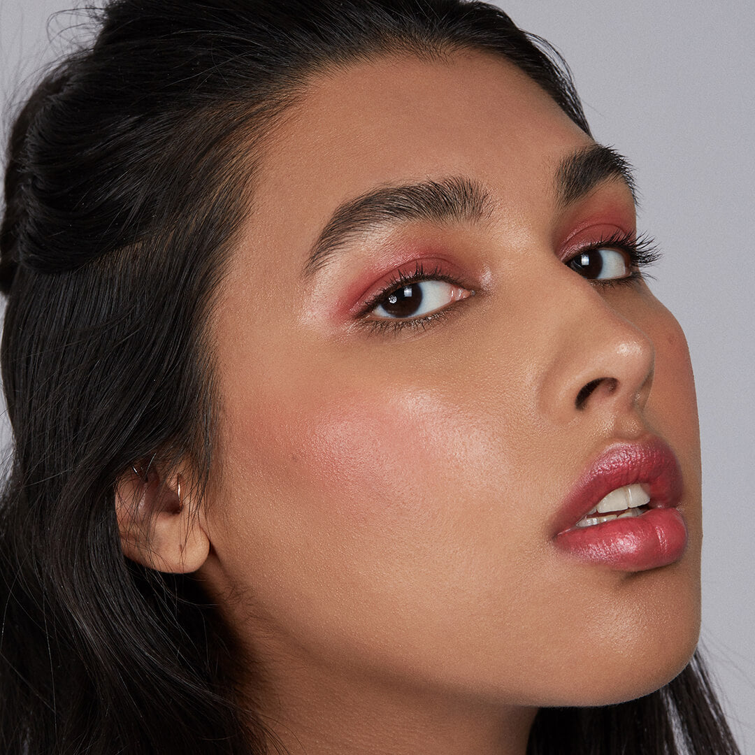 Close-up of a woman with makeup on a plain background