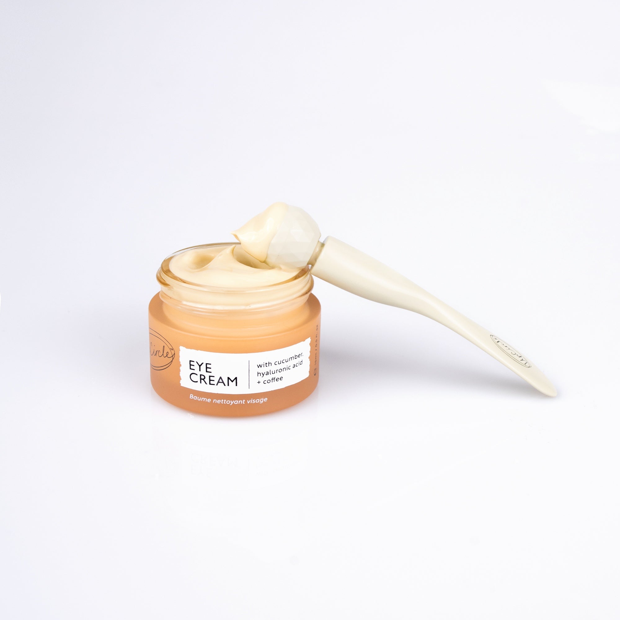 Jar of eye cream with a applicator on a white background