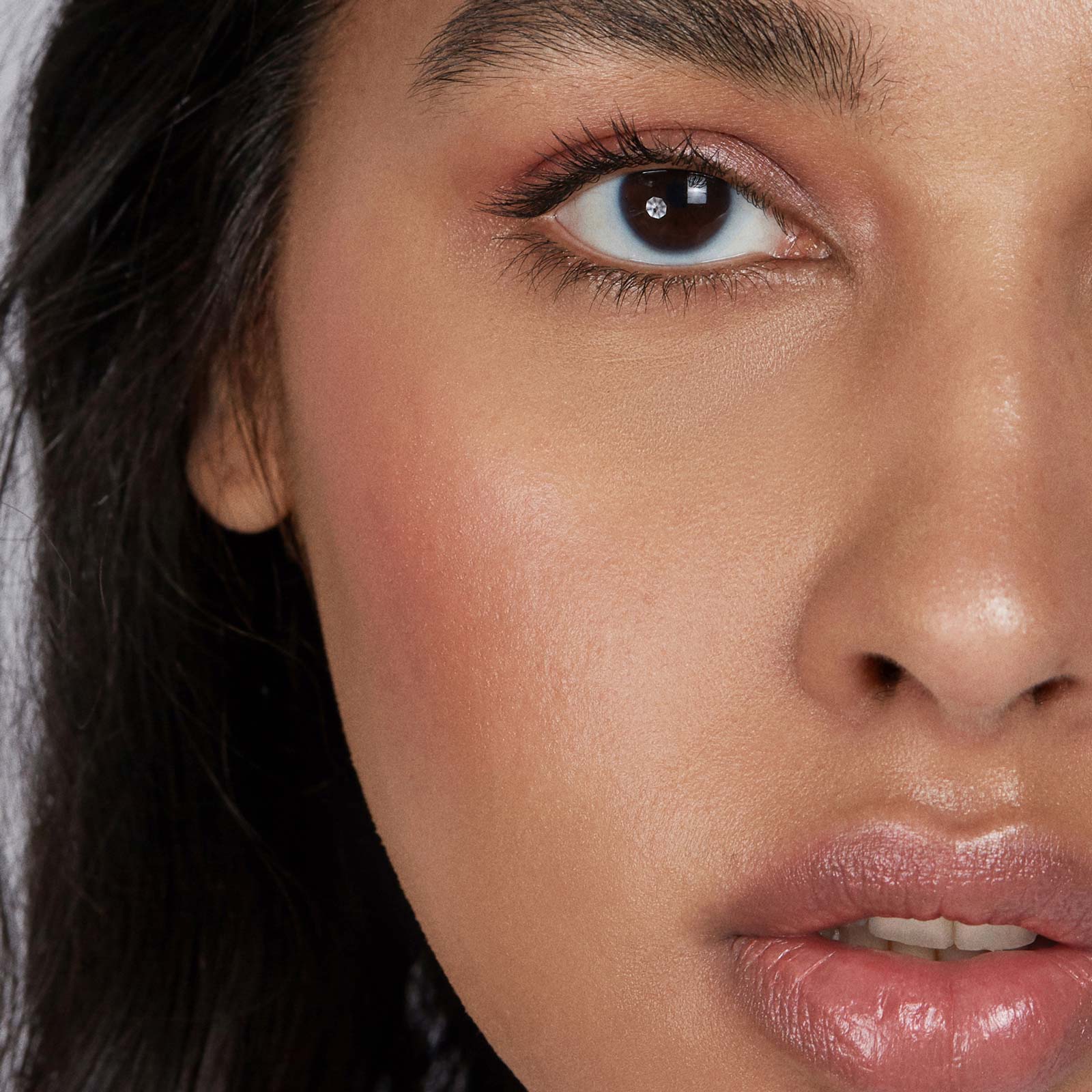 Close-up of a woman's face wearing makeup with a neutral background