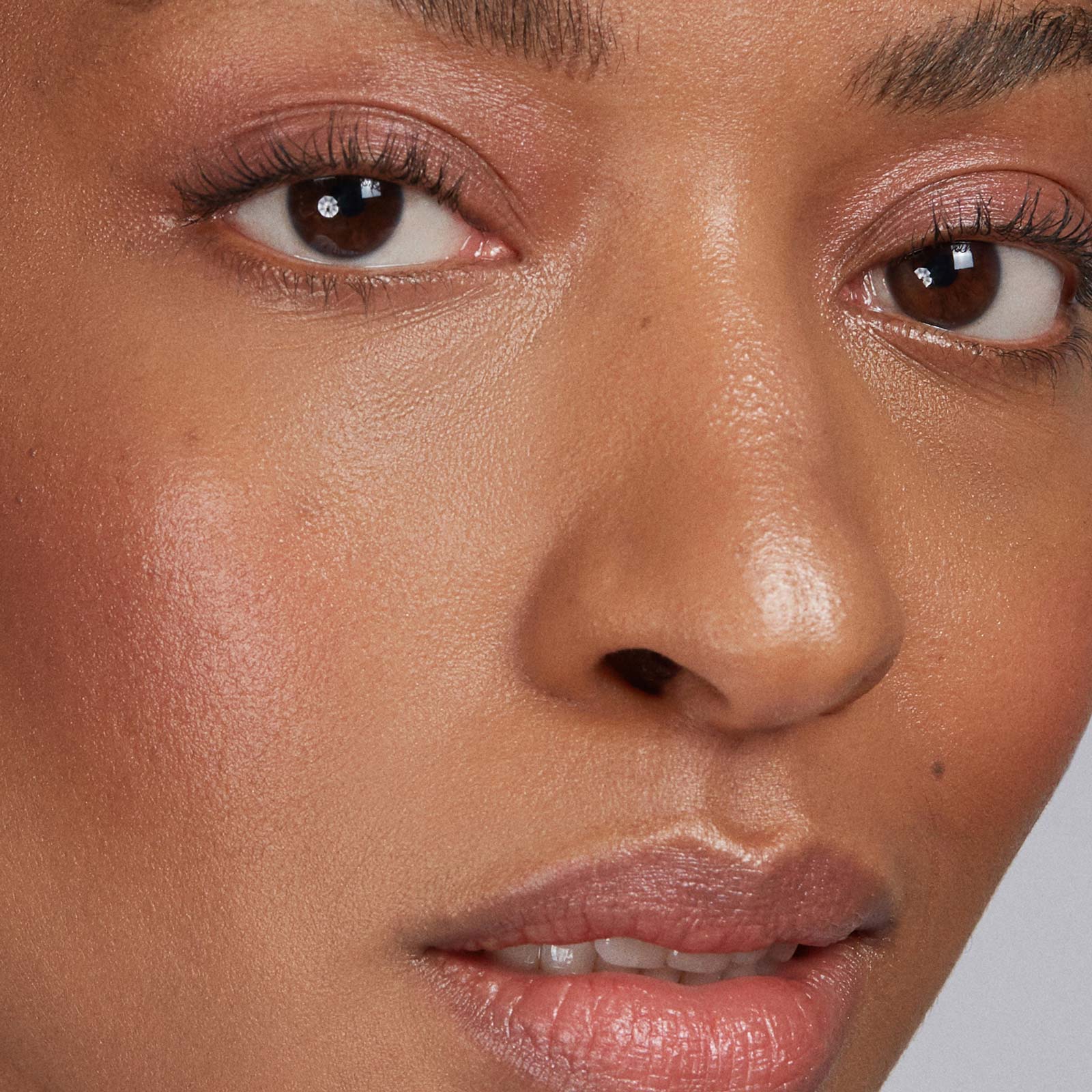 Close-up of a person's face with makeup and a neutral background