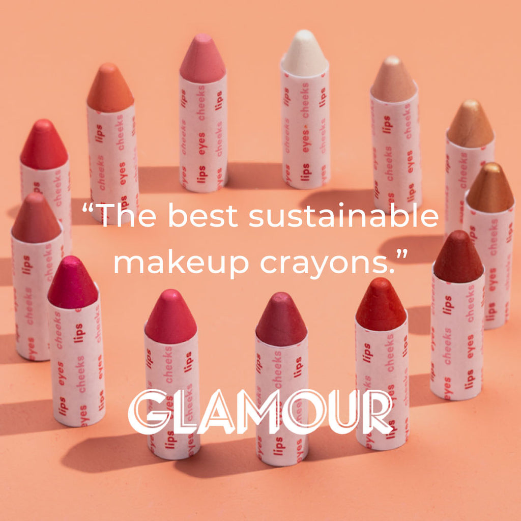 Makeup crayons with text on an orange background, featuring the brand 'GLAMOUR'.