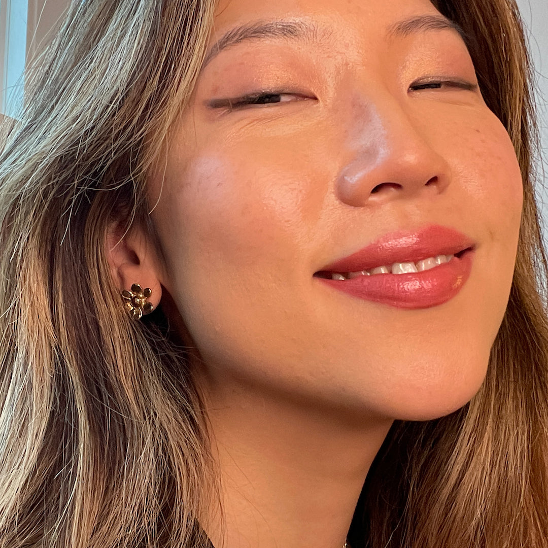 Close-up of a woman with a soft smile, wearing makeup.