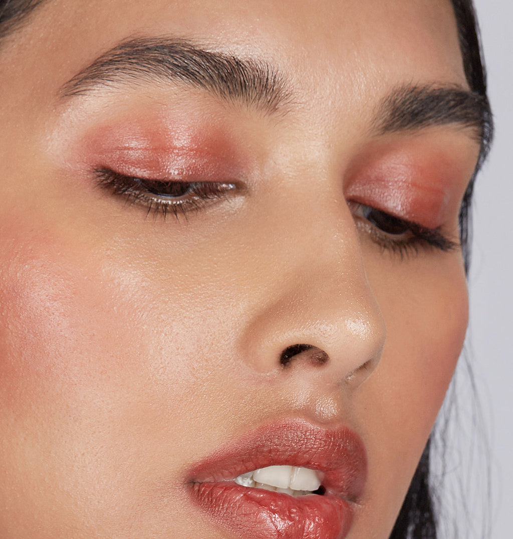 Close-up of a woman's face with pink eyeshadow and red lipstick.