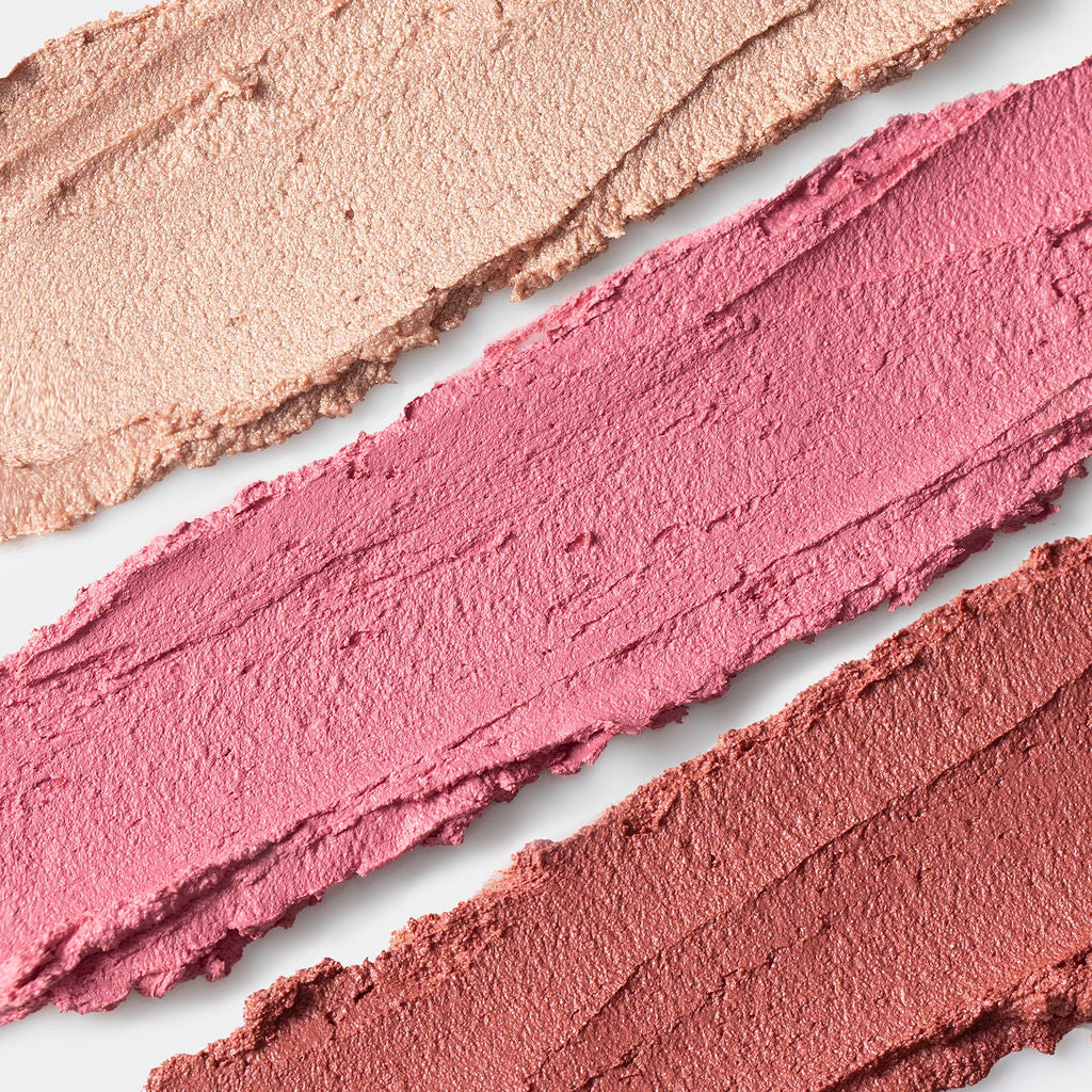 Three swatches of different pink makeup shades on a light background