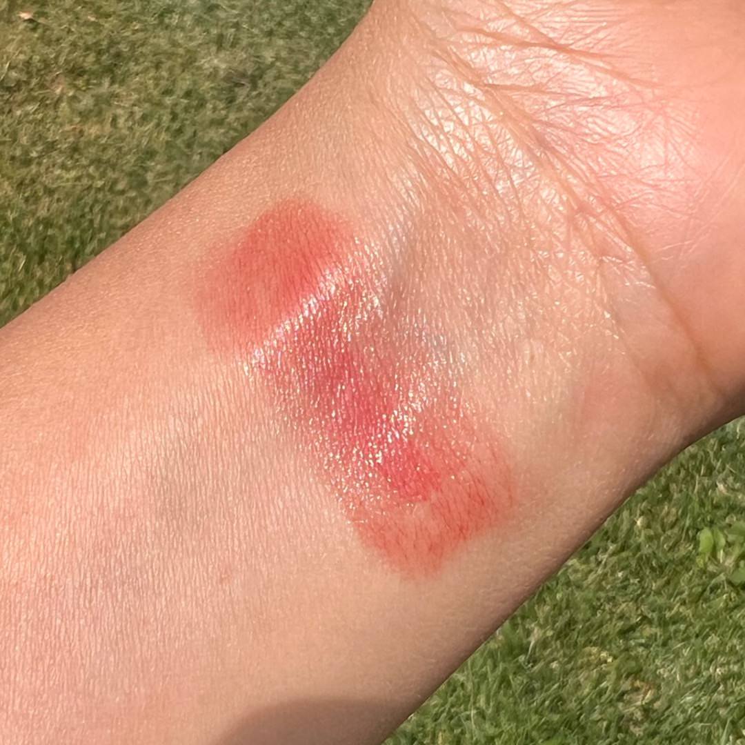 Close-up of a markeup swatch on a person's arm with a grassy background