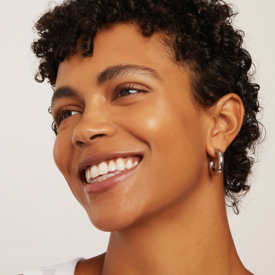 Close-up of a woman with a bright smile wearing foundation makeup on a plain background