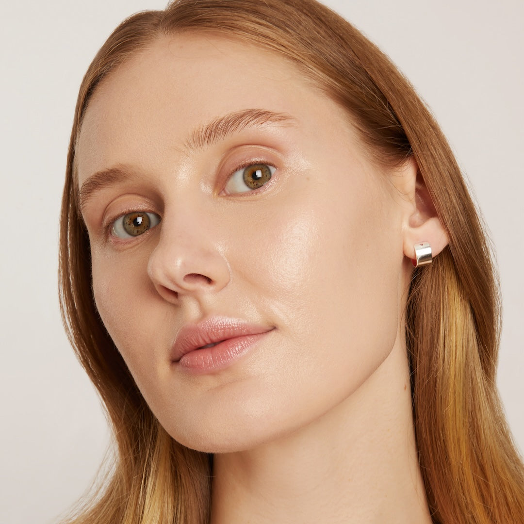 Close-up of a woman wearing foundation makeup on a plain background