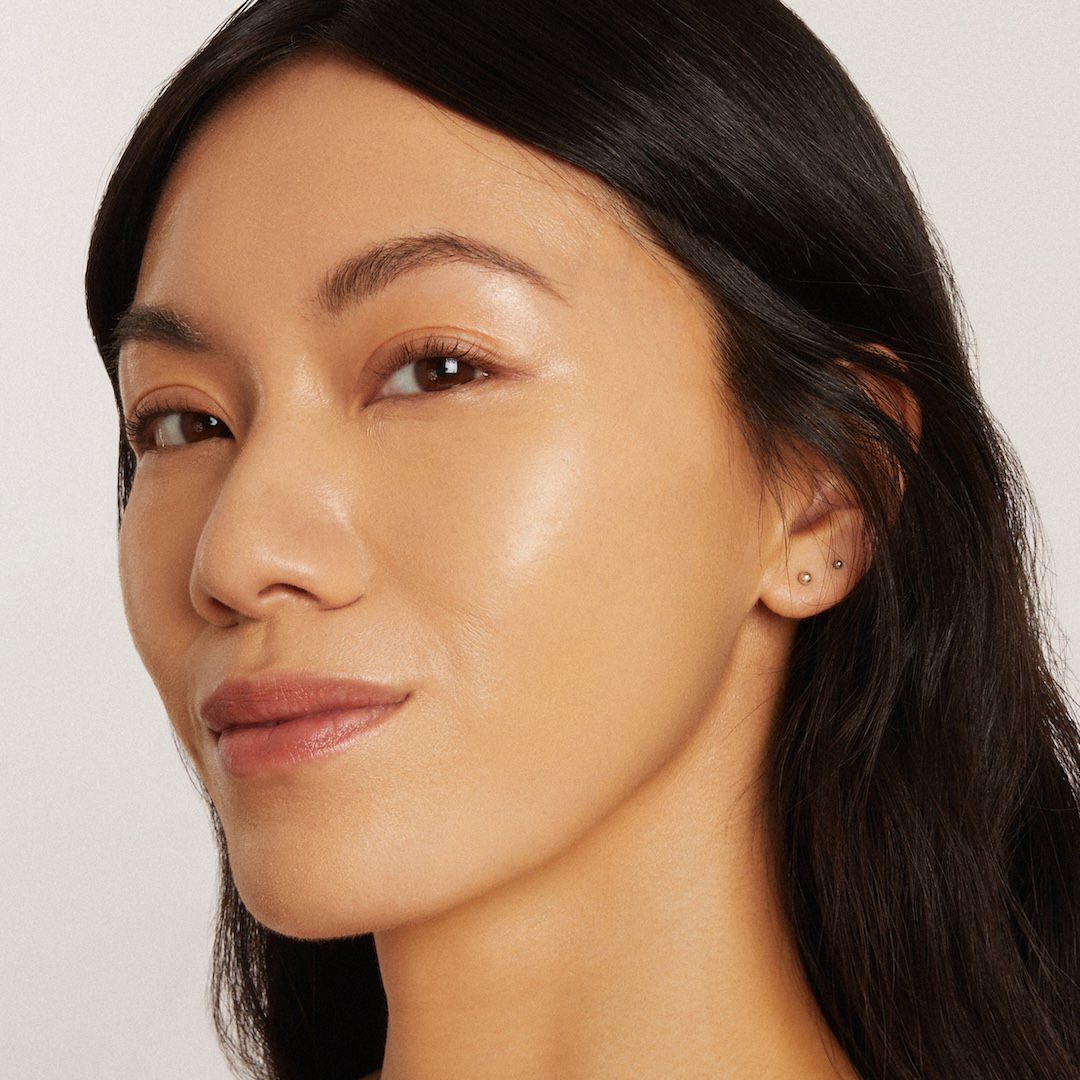 Close-up of a woman's face wearing foundation makeup with a neutral background