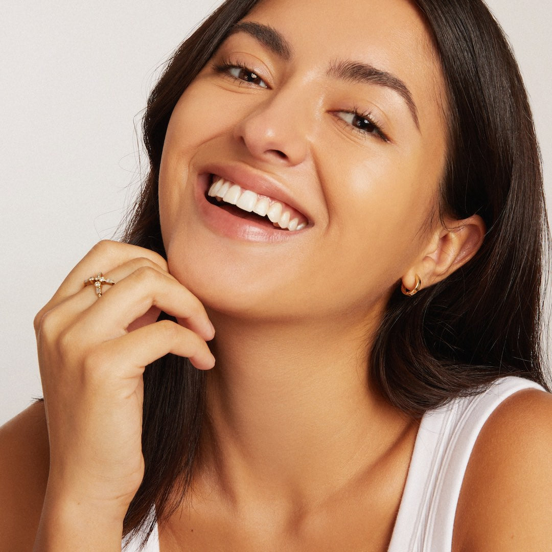 Woman with a bright smile wearing foundation makeup on a plain background