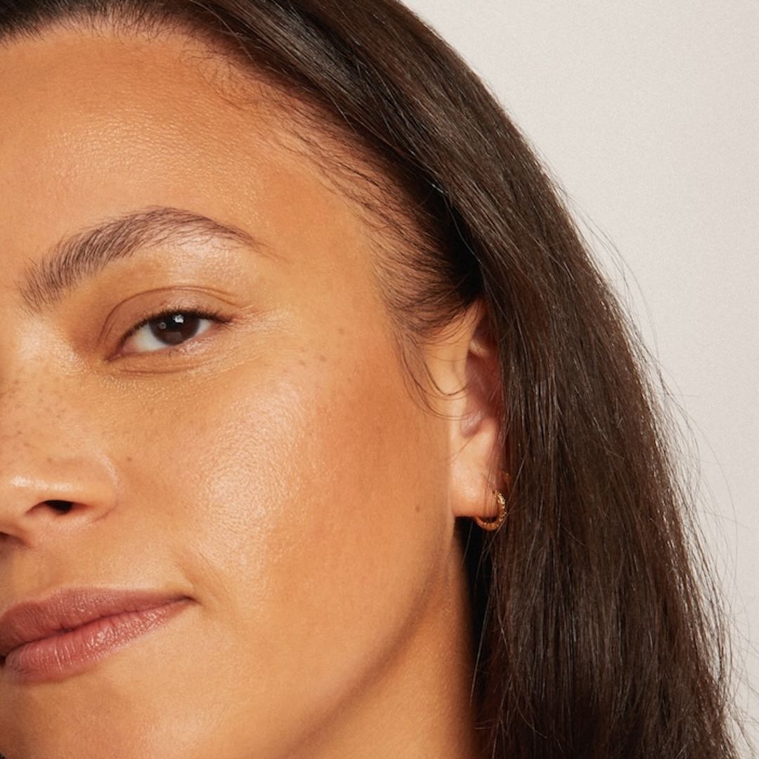 Close-up of a woman's face wearing foundation makeup with a neutral background