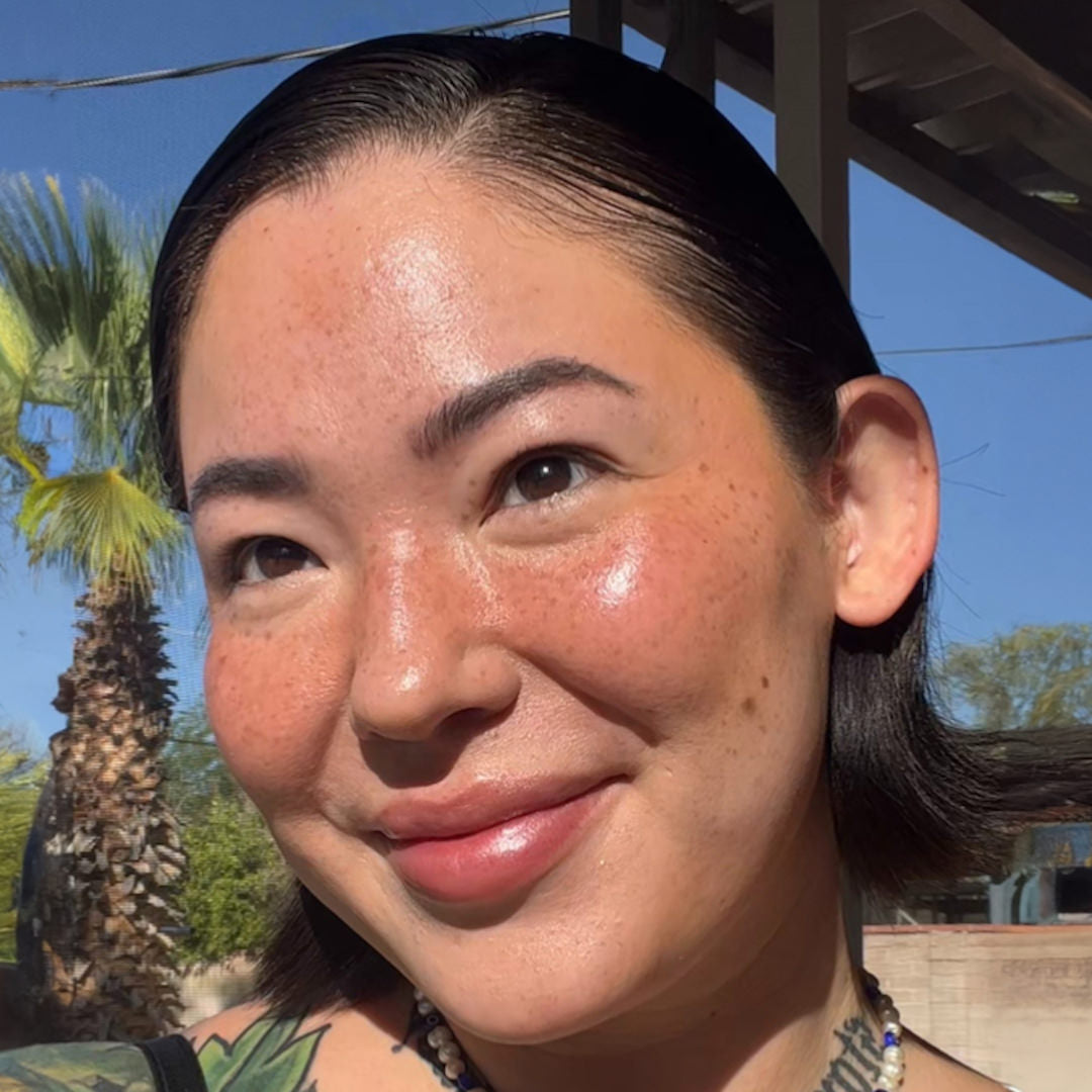 Woman with tattoos on her shoulder against a palm tree and clear blue sky background
