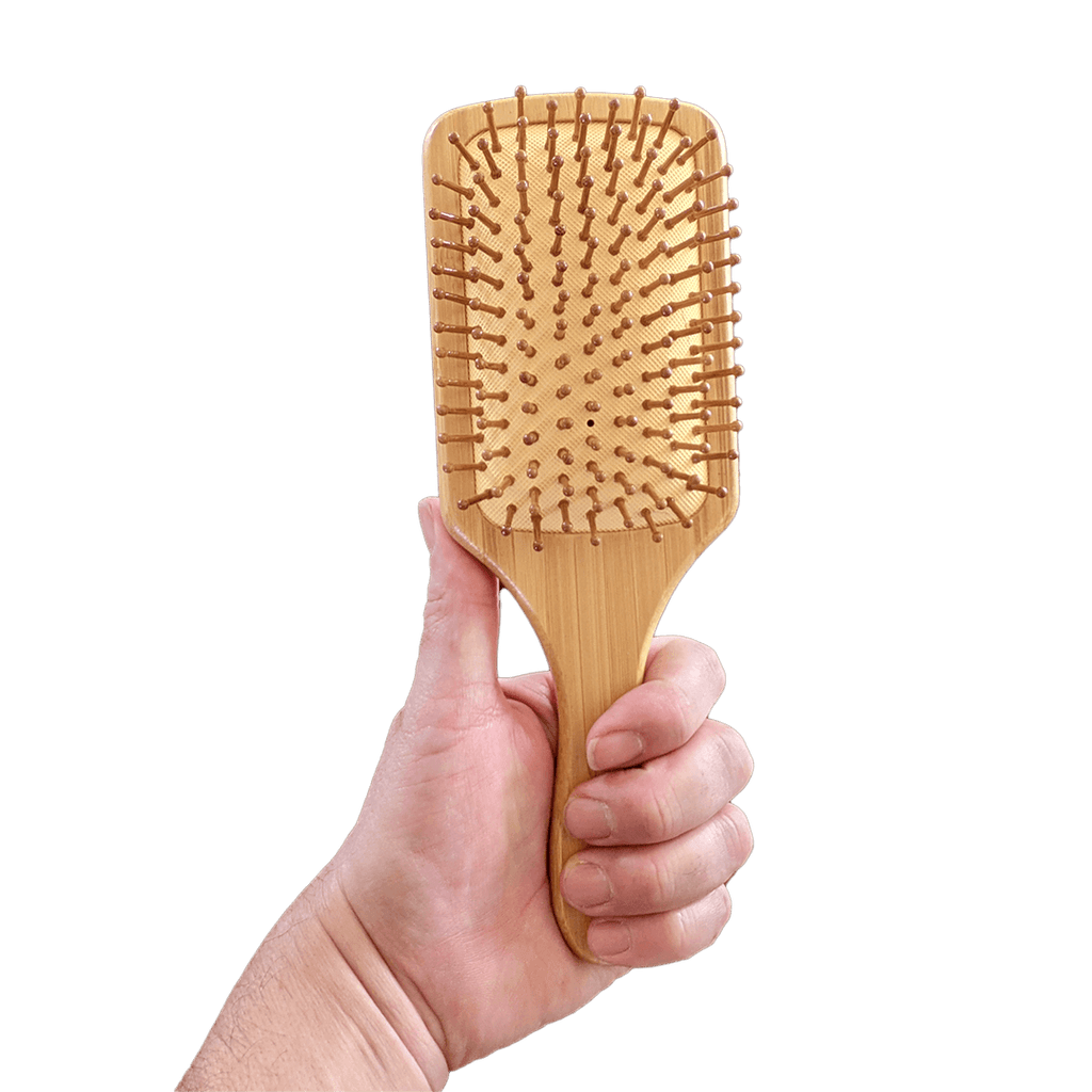 Hand holding a wooden paddle brush against a transparent background