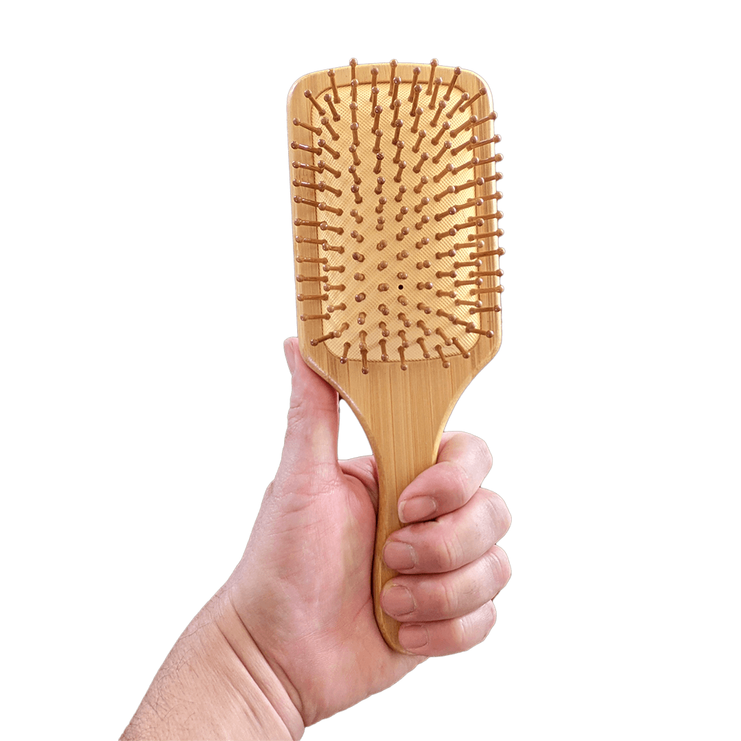 Hand holding a wooden paddle brush against a transparent background