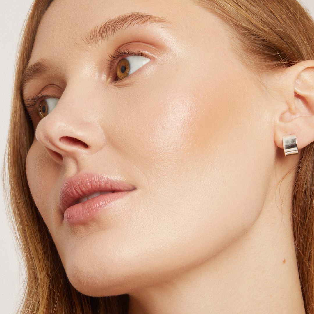 Close-up of a woman wearing foundation makeup on a light background