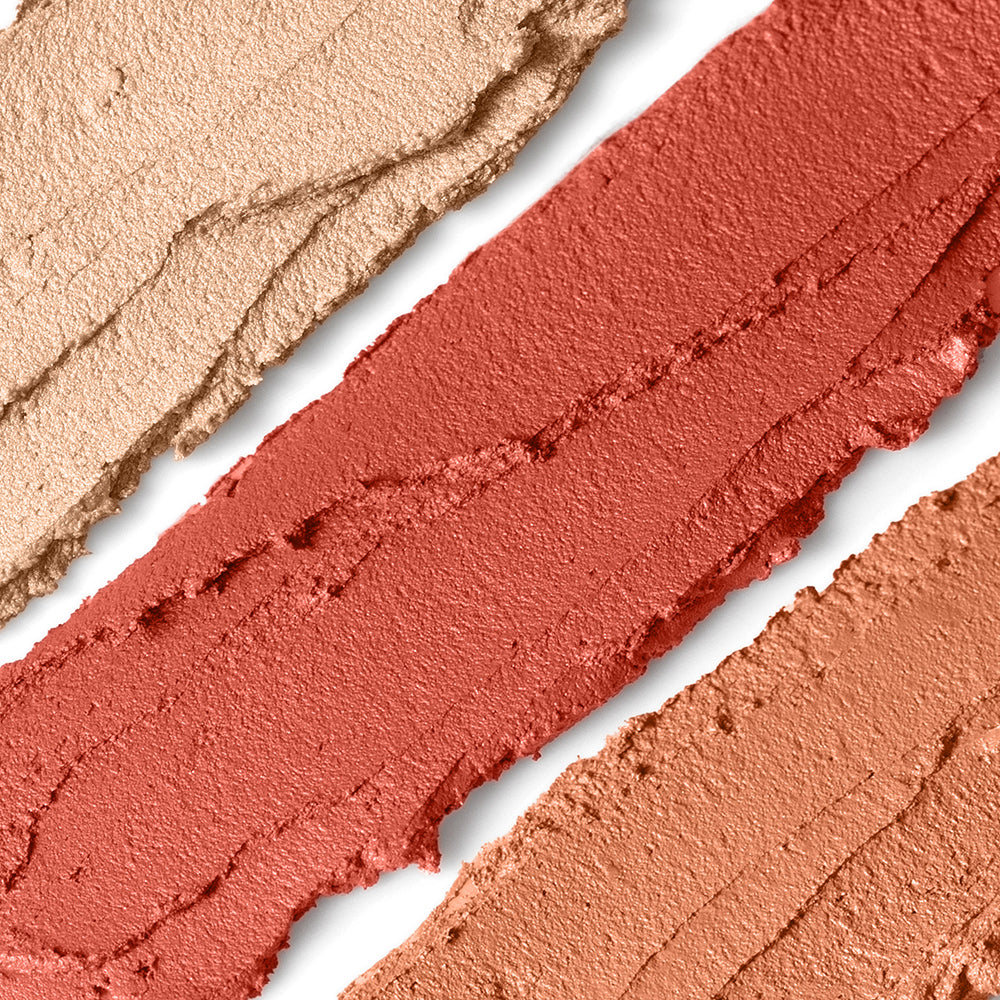 Close-up of three swatches of different peachy shades of makeup on a white background
