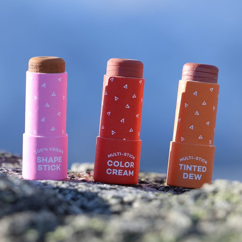Three cosmetic sticks with colorful packaging on a natural background