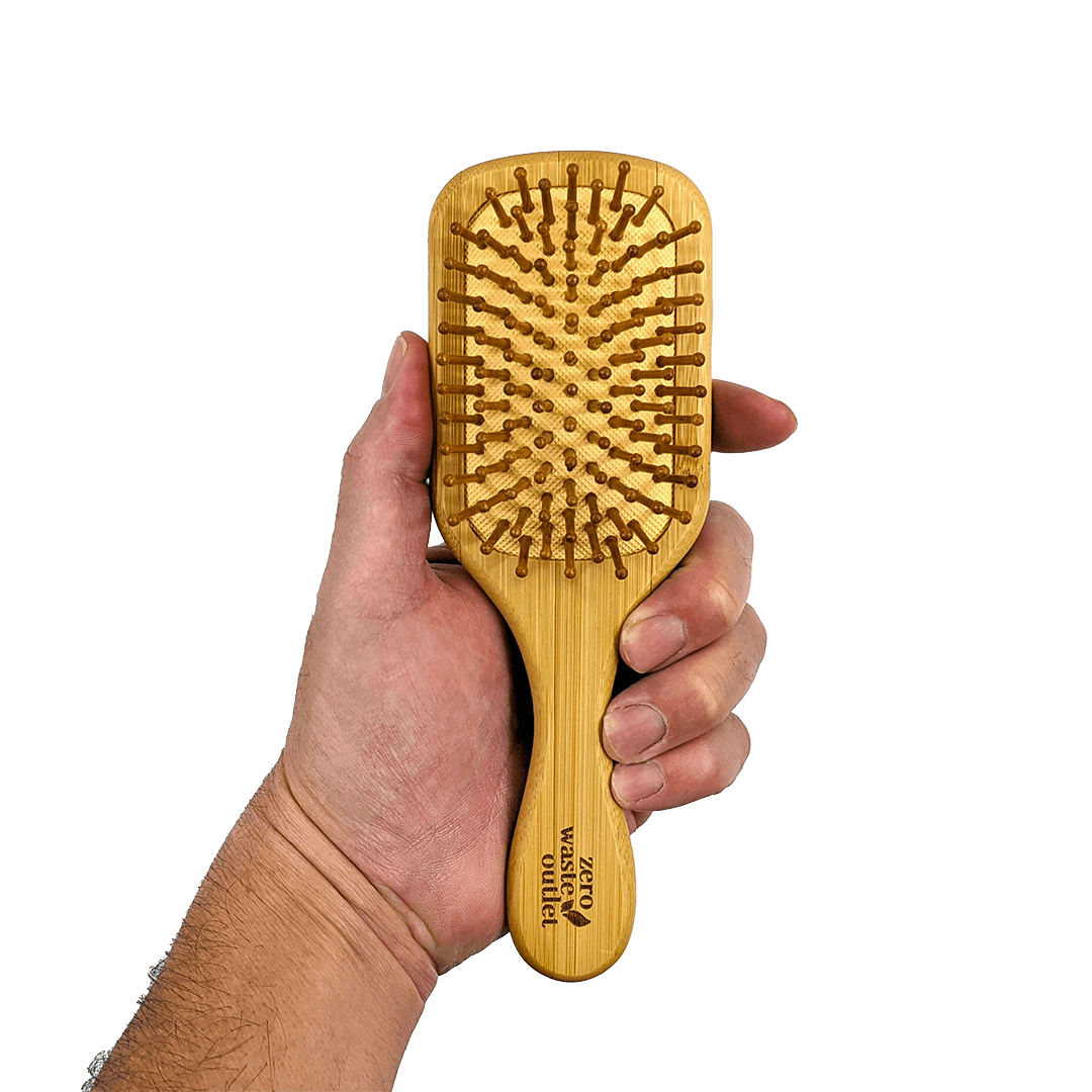Hand holding a bamboo paddle brush against a solid background