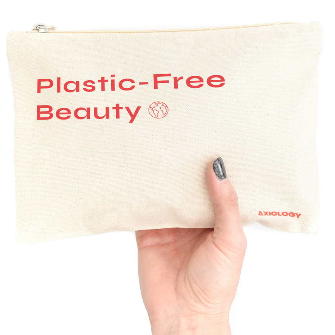 Hand holding a beige pouch with 'Plastic-Free Beauty' text and Axiology logo.