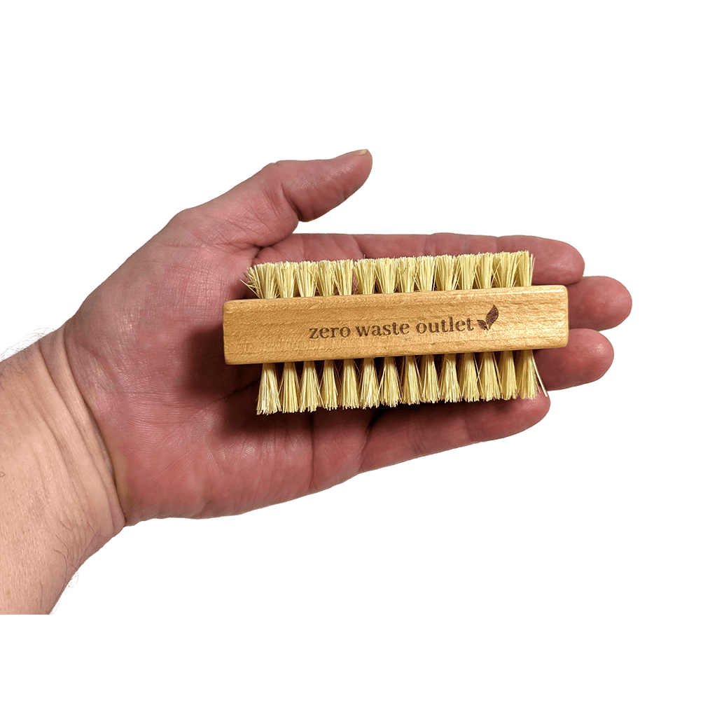 Hand holding a bamboo brush with natural bristles labeled 'zero waste outlet' against a transparent background