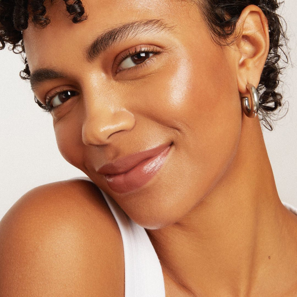 Close-up of a woman's face wearing foundation makeup with a neutral background