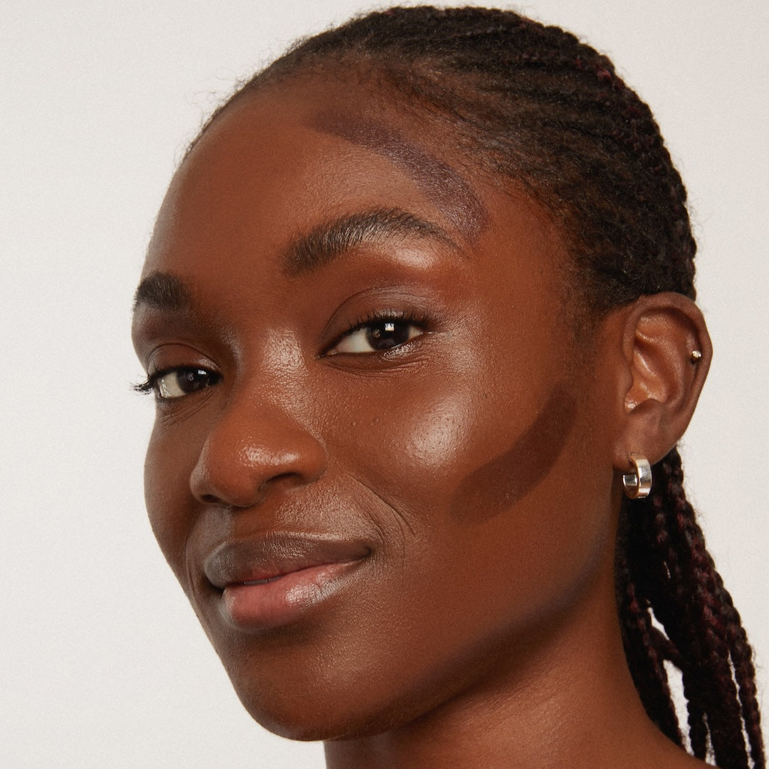 Close-up of a woman with braided hair against a plain background