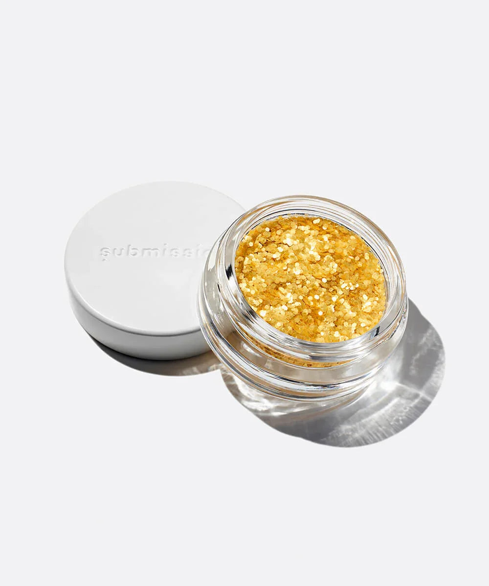 Gold glitter in a clear jar with a white lid on a light gray background