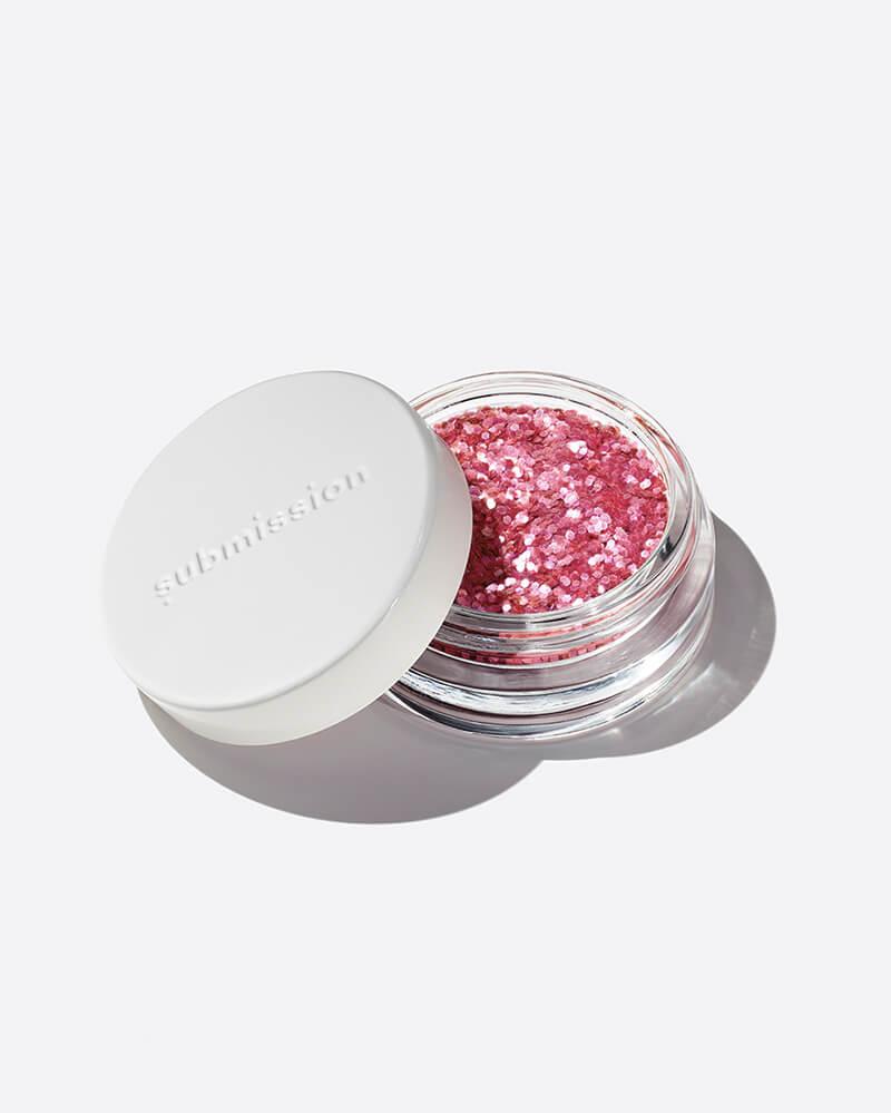 Pink glitter in a small open container with a white lid on a light gray background