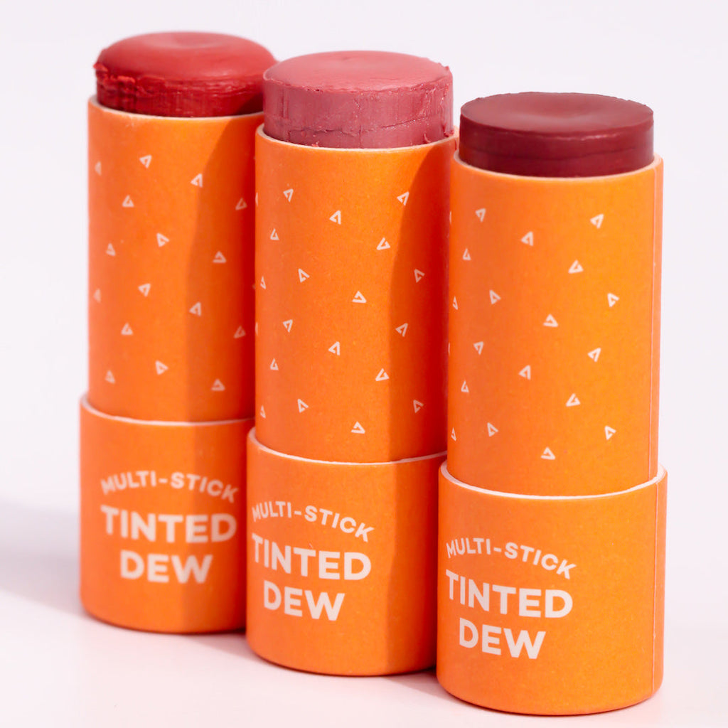 Stack of orange 'Multi-Stick Tinted Dew' products on a white background