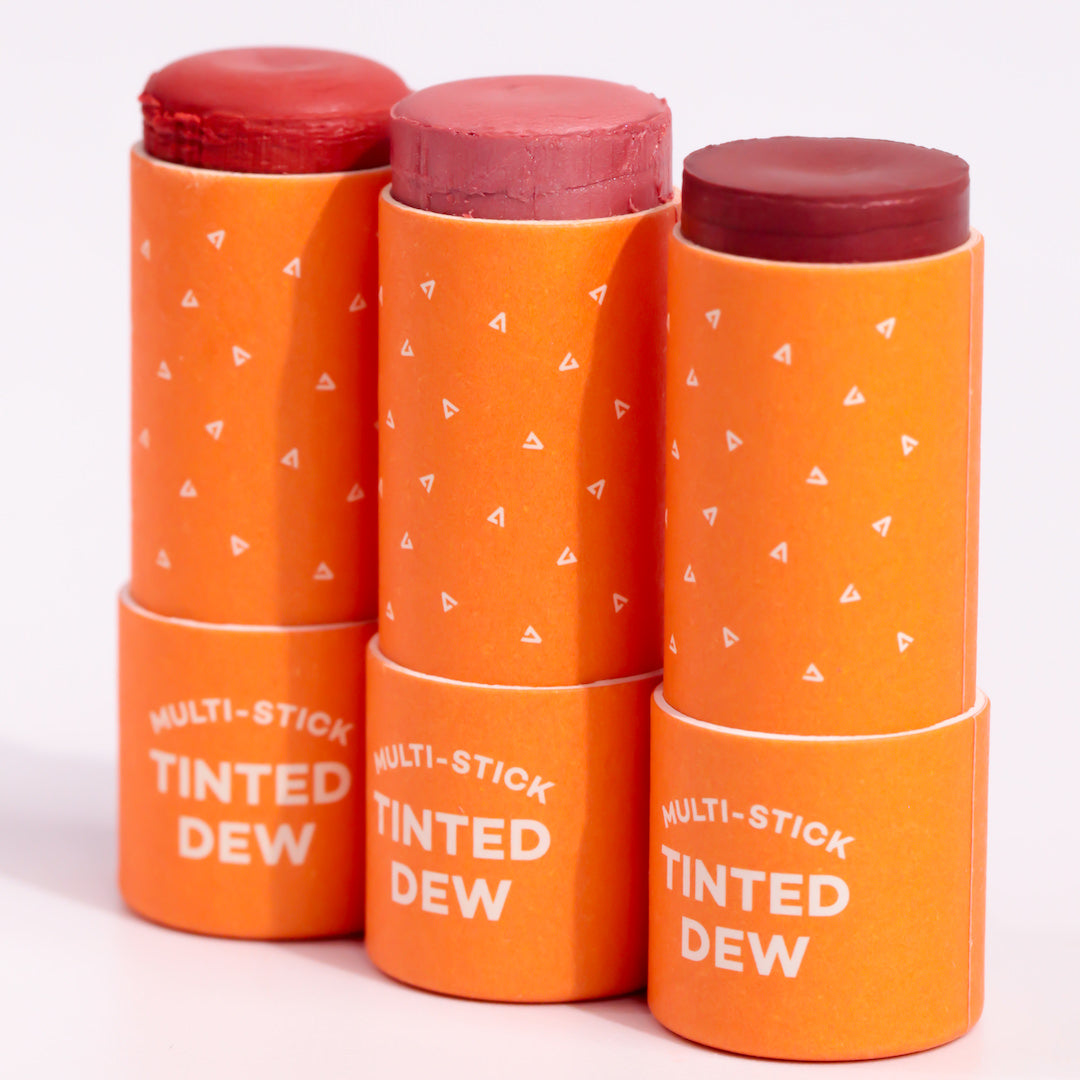 Stack of orange 'Multi-Stick Tinted Dew' products on a white background