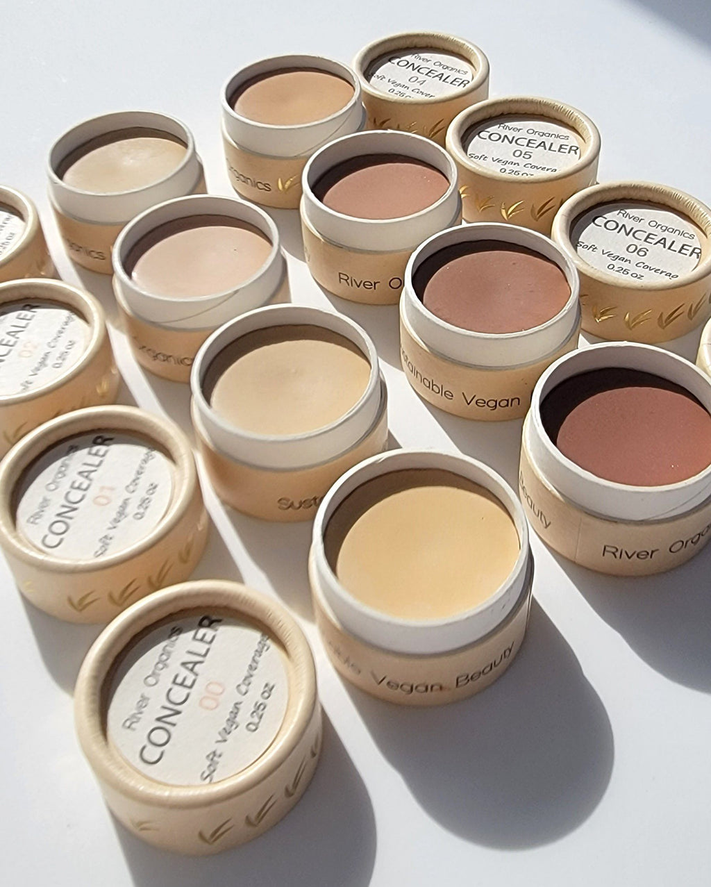 Collection of concealer pots with various shades on a light background