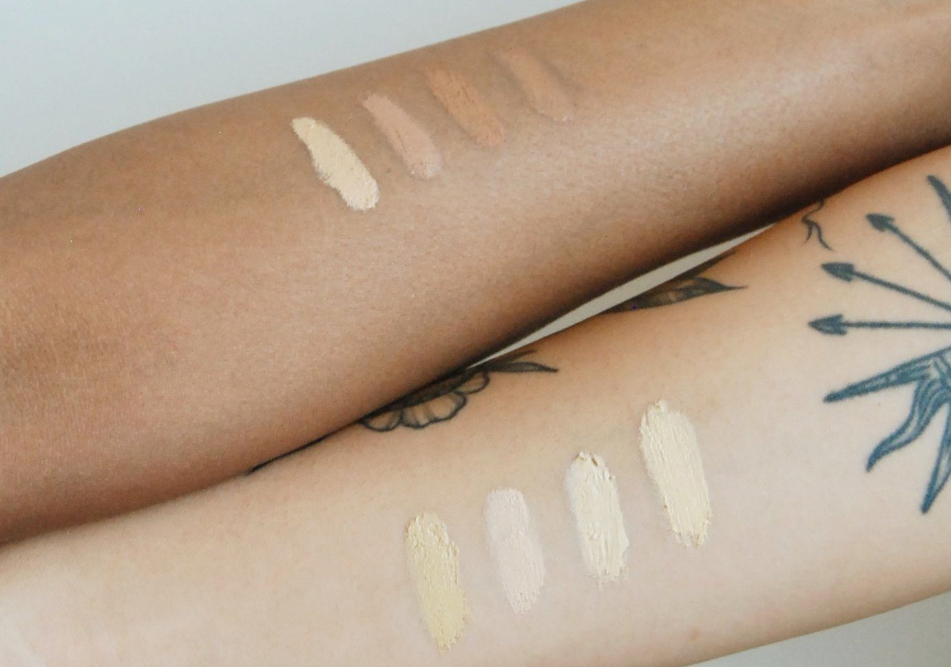 Two arms with makeup swatches on a neutral background